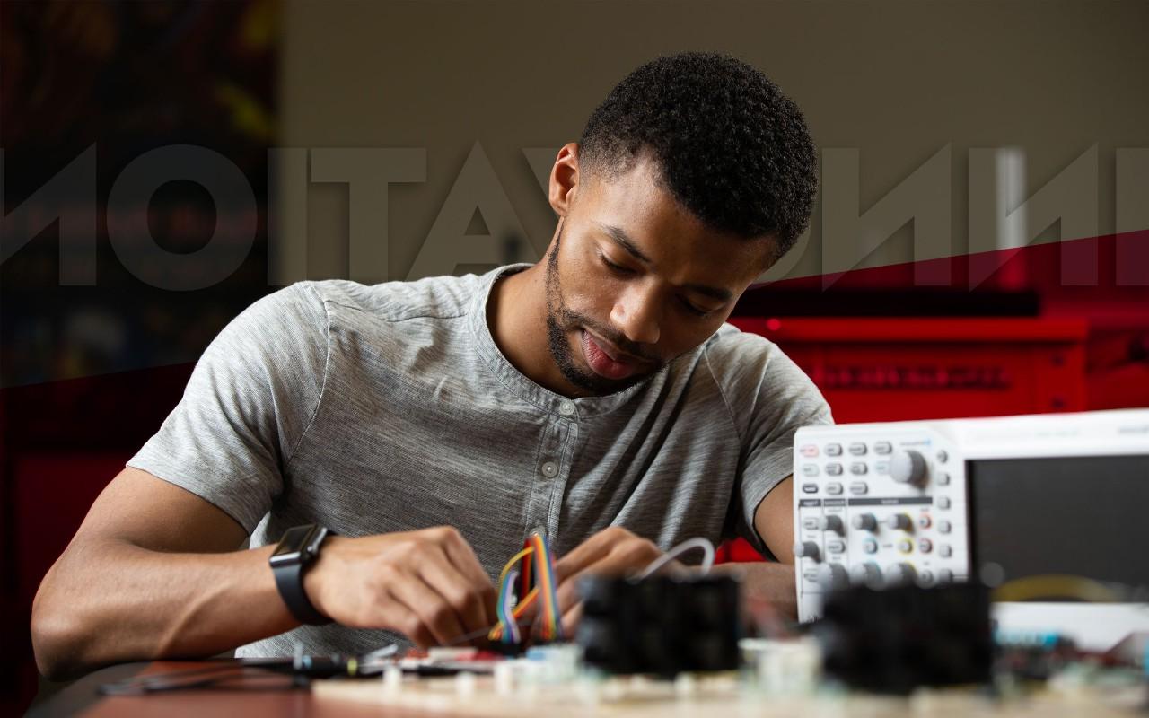 最大的博彩平台大学工程系的一名学生正在制作电路板